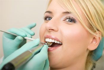 eine junge Frau im Behandlunszimmer des Zahnarztes und der Zahnärztin