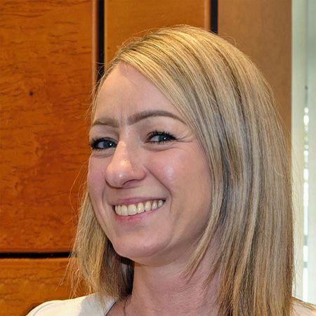 Frau Friedmann, freundlich lächelnd, wartet an der MedicaDenta Rezeption auf die Patienten.