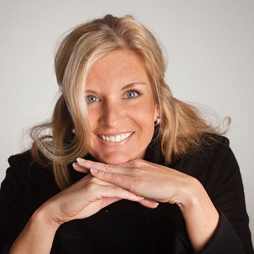 Frau Dr. Alexander Steup stützt ihr Kinn auf beide Hände und lächelt freudig