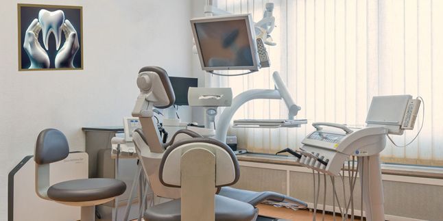 Zahnarztpraxis mit Behandlungsstuhl, Geräten und moderner Zahn-Collage an der Wand