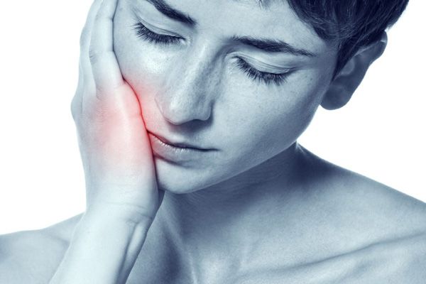 Patientin hält die Hand an die schmerzende Wange