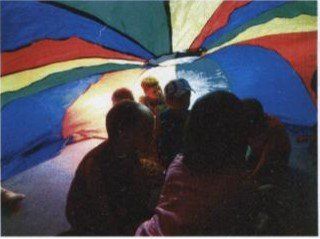 Kinder beim Krabbelgottesdienst unter dem Regenbogen-Fallschirm