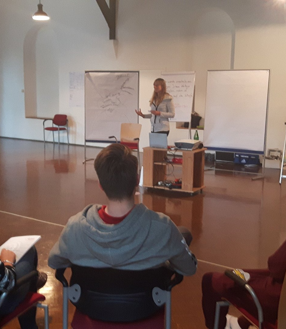 Seminarraum mit Menschen im Plenum, Manuela Kurtenacker hält einen Vortrag