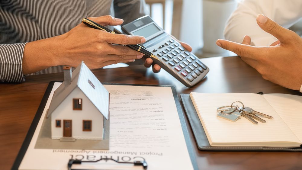 Property Manager Hands using calculator next to house model and tenancy contract