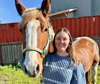 Nicole standing next to a tall horse.