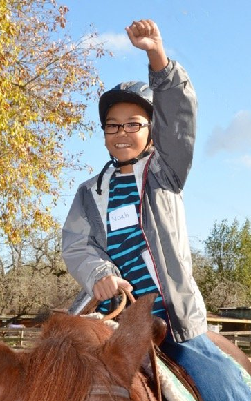An adolescent boy feels excited and proud as he rides a horse.