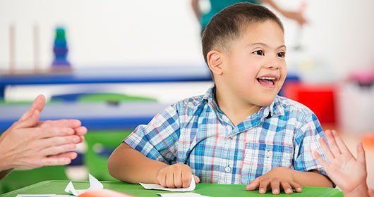 Child sitting at a table smiling.