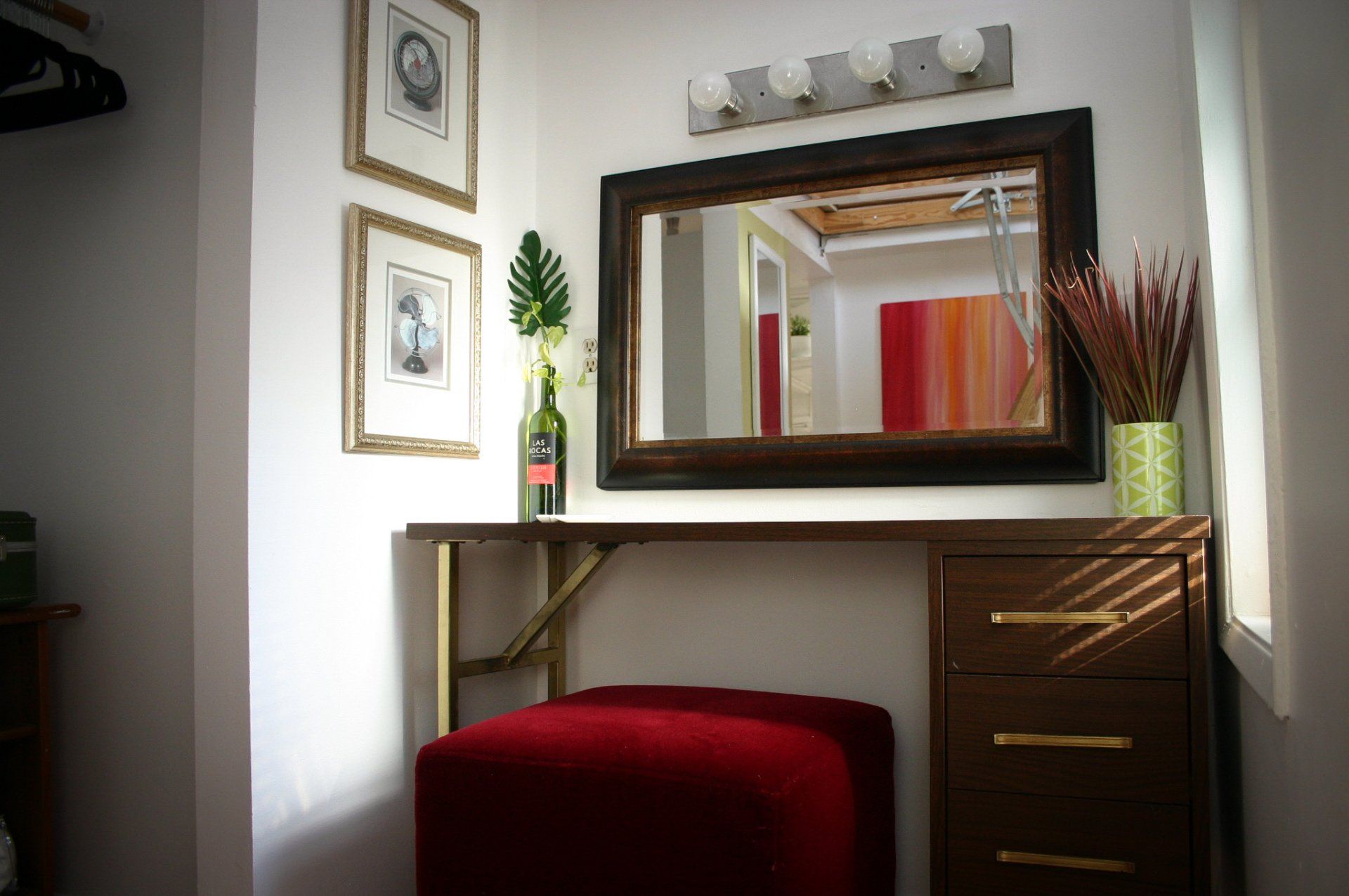 retro desk turned into a vanity with rectangle mirror under dressing room lights, red velvet cushion seat
