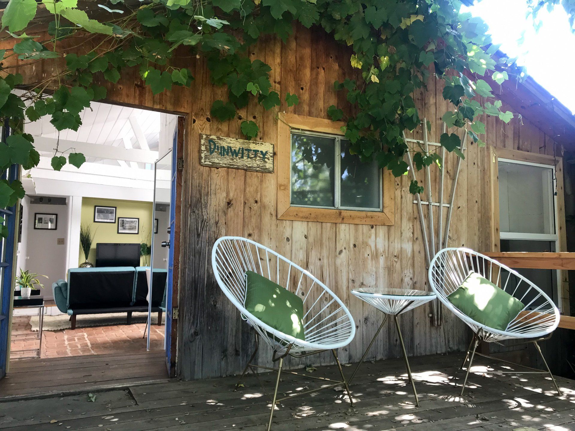 front deck elevated with white acapulco chairs, side table and green pillows