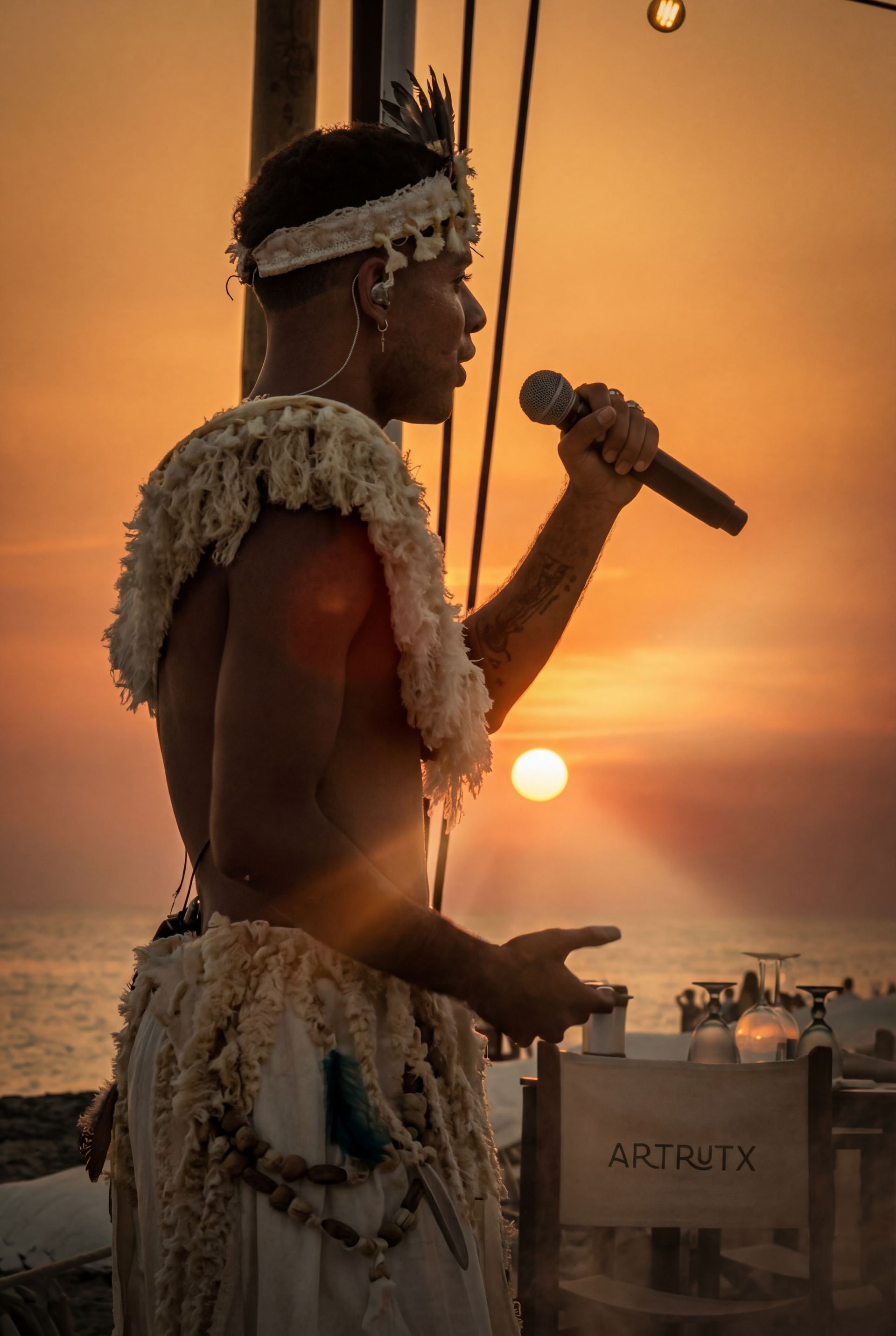 Artista cantando con micrófono al atardecer, imagen cinematográfica del espectáculo Kahuna de Are You Ready