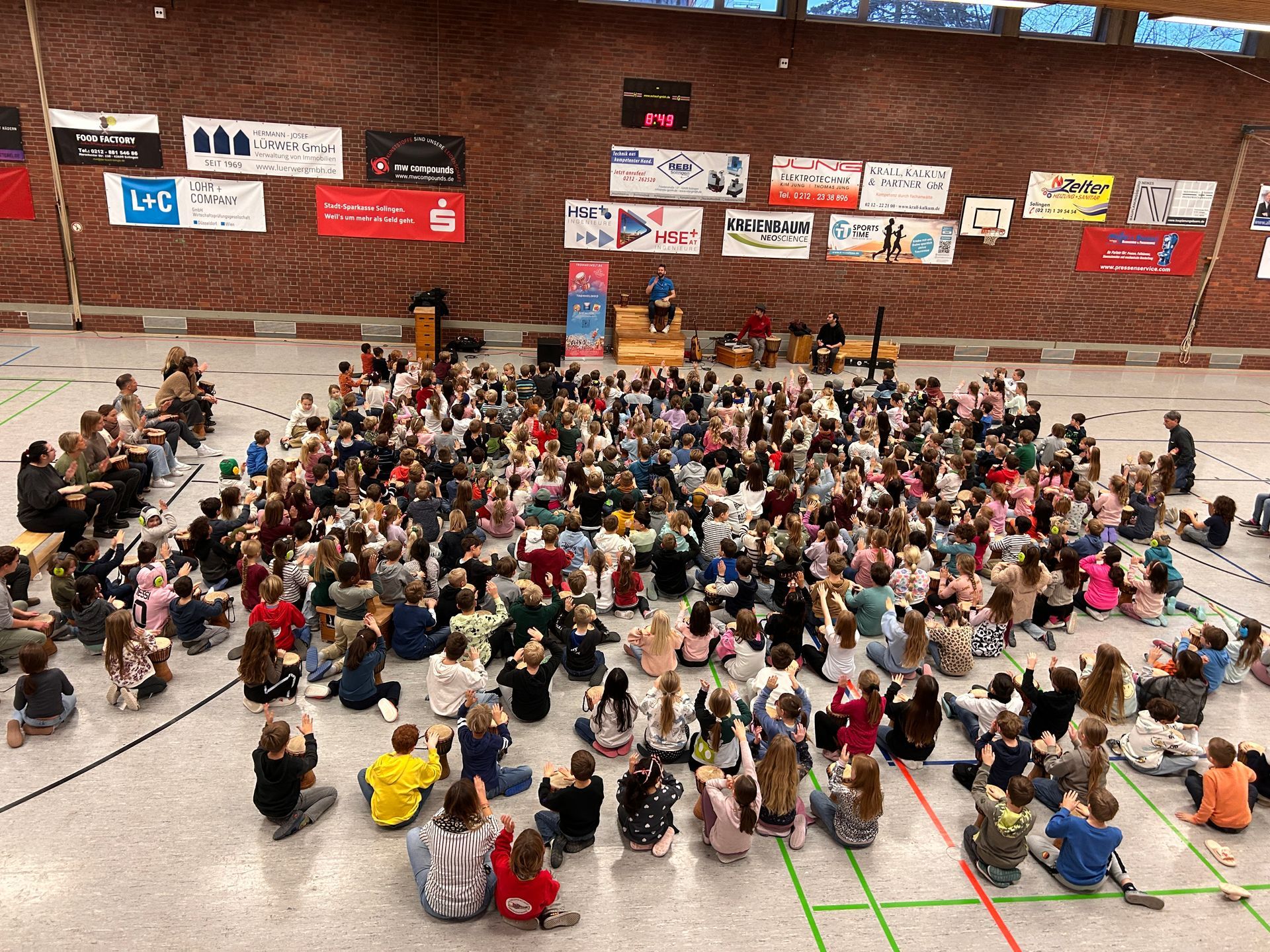 Kinder in der Turnhalle, die im Kreis sitzen und trommeln