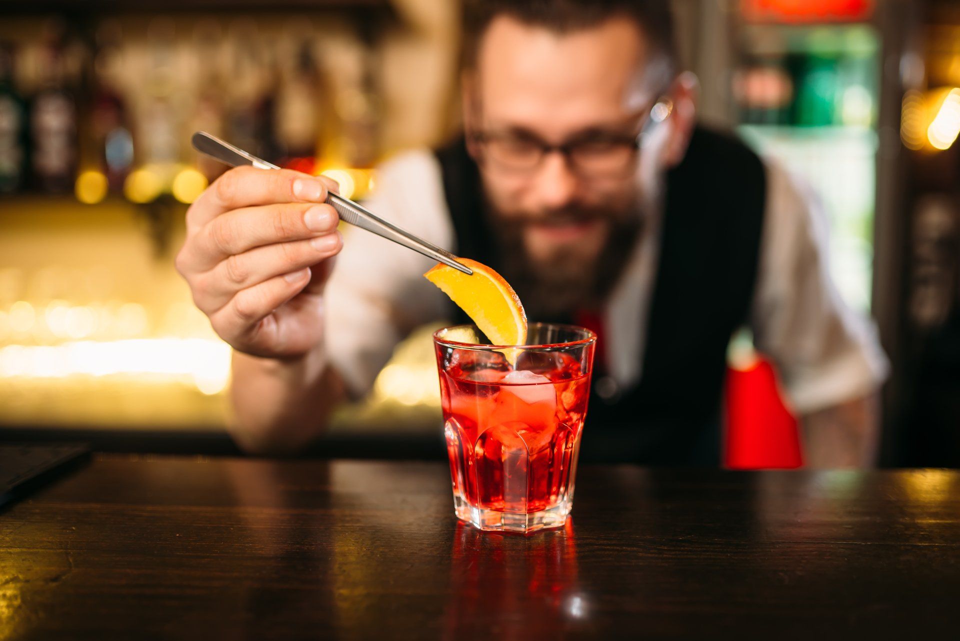 Barman préparant un mocktail rouge garni d’orange – formation cocktails sans alcool, recettes créati