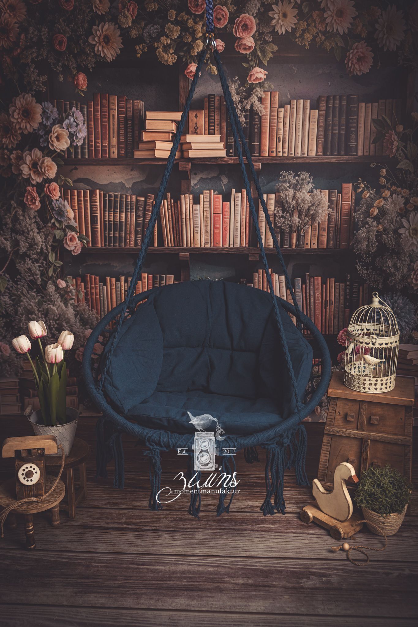 Mini-Aktion Frühlingskapitel Fotoaktion Frühlingskapitel, Fotoset mit einer blauen Netzschaukel, im Hintergrund eine Bücherwand umgeben von pastellfarbigen Blumen