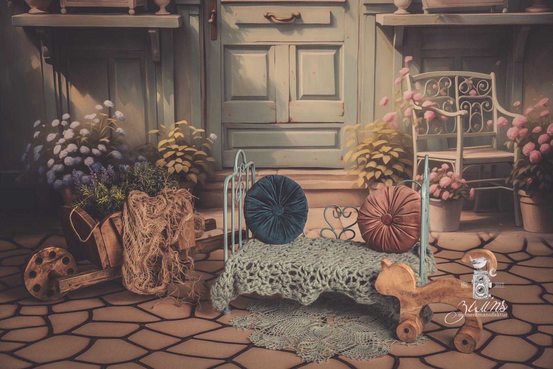 Fotoset für Neugeborene mit blauem Metallbett vor einem Hintergrunf mit blauer Tür und Garten