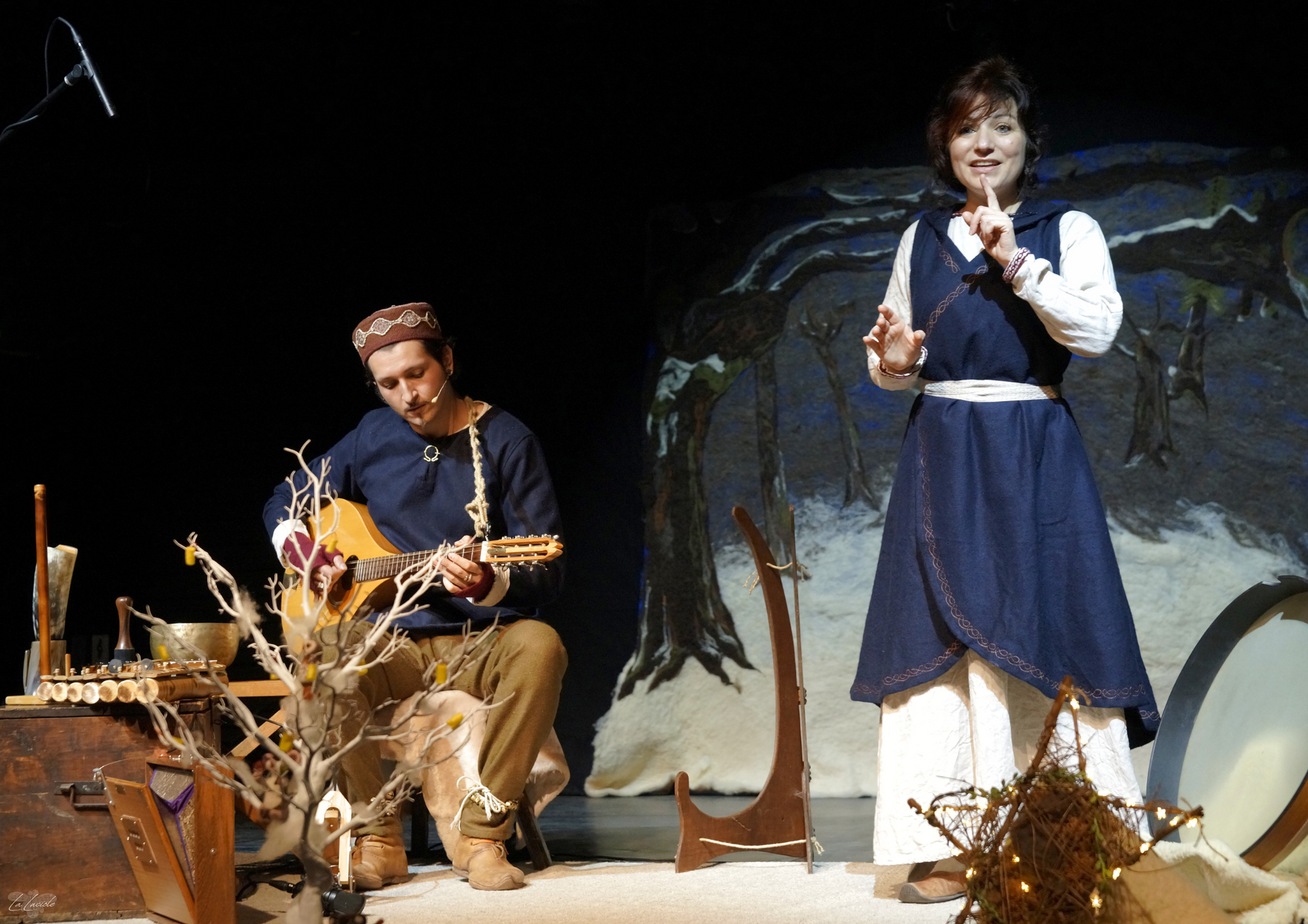 un musicien et une conteuse sur scène décor hivernal contes de yule