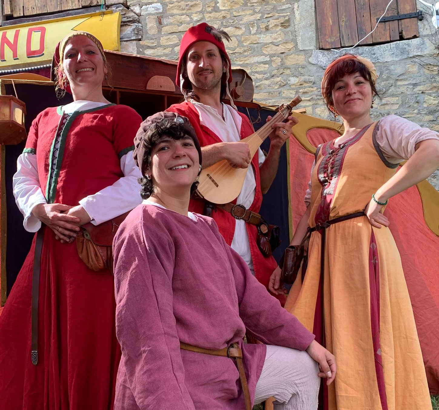 4 comédiens en costume médiévaux posant devant la charrette des bateleurs