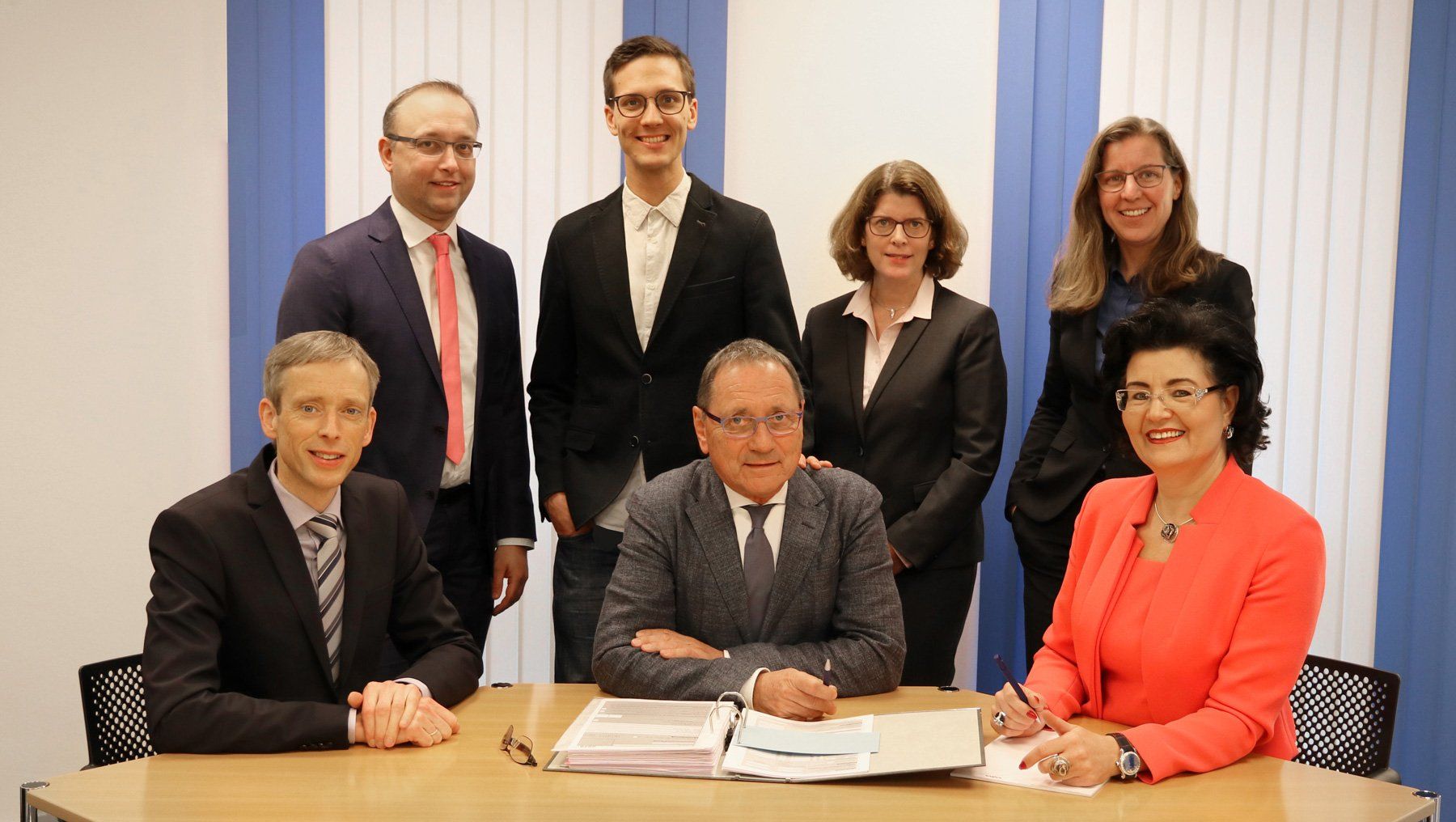 Gruppenbild mit allen Steuerberatern von W+M in einem Büro. Drei Personen sitzen und vier stehen dahinter.