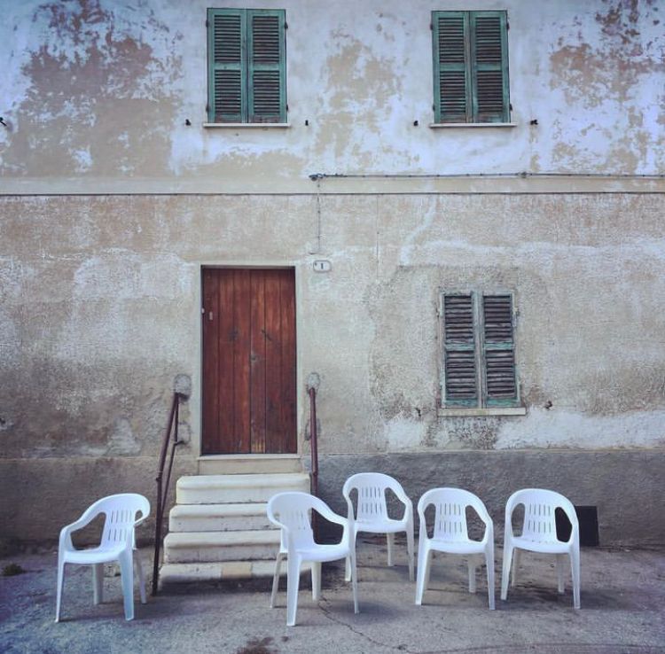 plastic chairs in rural context n front of a faded yellow country house