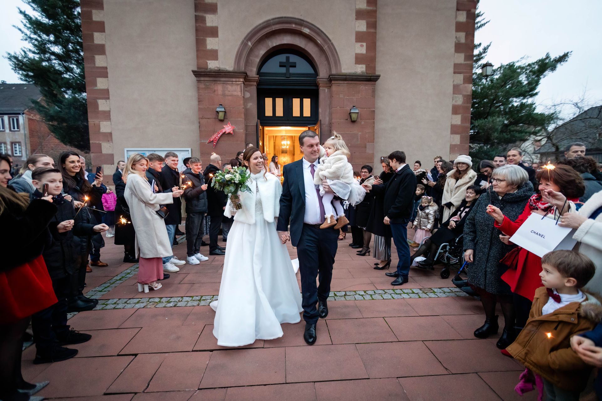 Mariage de Olivia et Jérôme à bischwiller Couple devant une église entrain de se remettre à chacun une alliance. Cette photo a été prise par un photographe en alsace appellé Sauvage Raphael.
On peut apercevoir au fond de la photo un croix représentant l'église ou il se marie. Juste à coté de cette croix on voir le pasteur qui souris. Les mariés sont en plein éclat de rire.