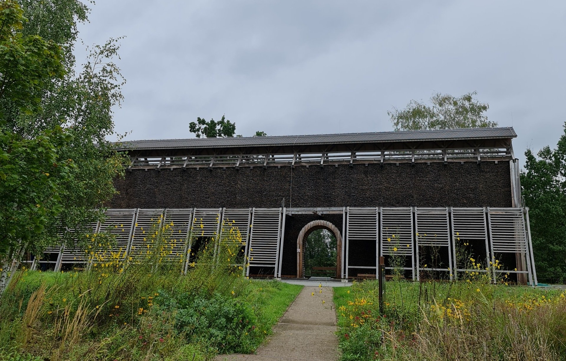 Auf dem Weg zum Gradierwerk im Bürgerpark Oelsnitz Erzgebirge Photo by; Viola Einert-Krug Gradierwerk, hohes Gebäude aus Holz mit Reisig, Blumen und Wiese davor