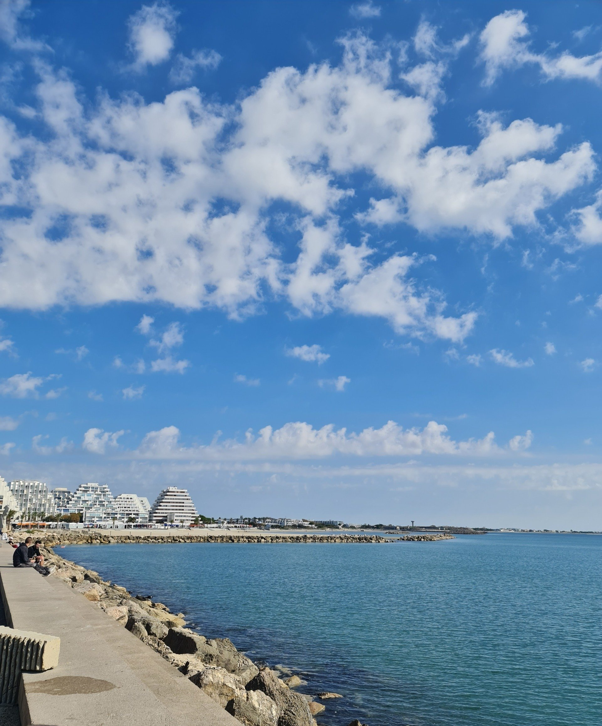 links Promenade am Meer im Hintergrund die Skyline der Häuser von La Grande Motte