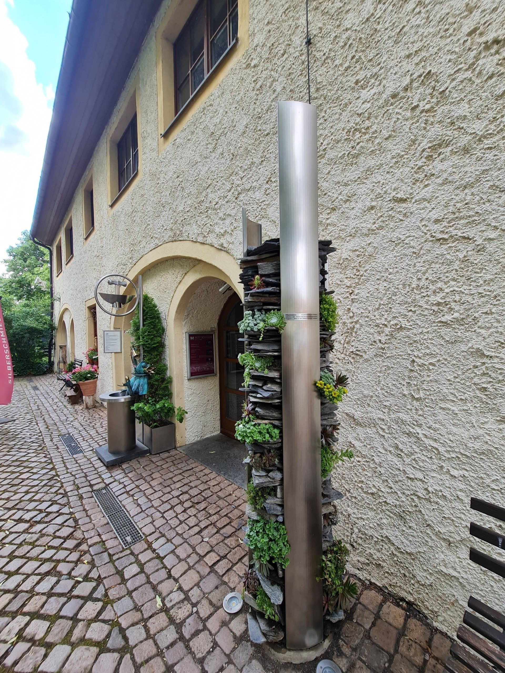 Hausmauer und Silberstatue mit Sukkulenten