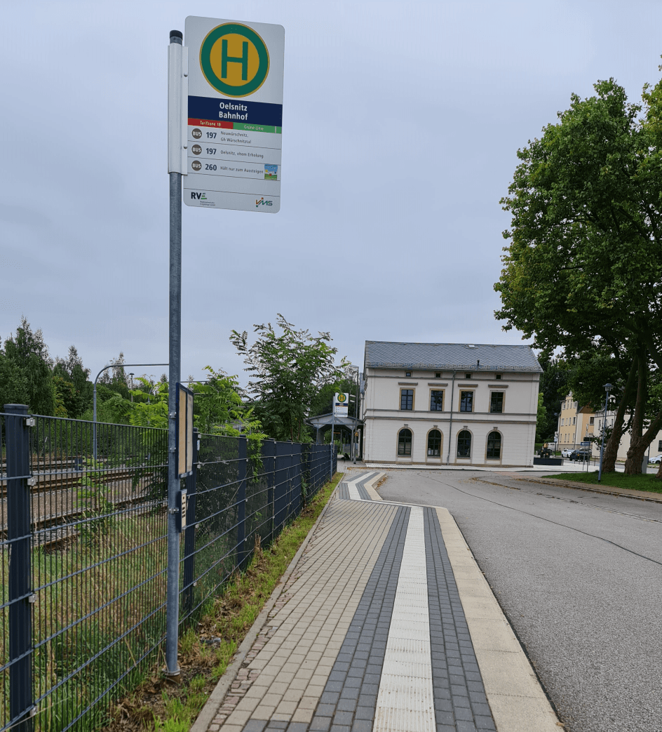 Gleich hinter dem Bahnhof befindet sich der Eingang zum Bürger und Familienpark in Oelsnitz im Erzgebirge Photo by: Viola Einert-Krug Bushaltstelle und Bahnhofsgebäude Zaun und Häuser Oelsnitz Erzgebirge