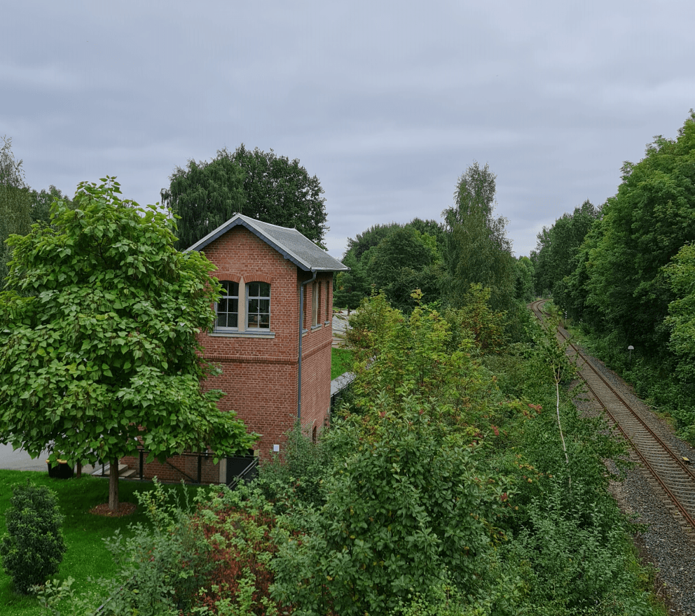 Links im Bürgerpark Oelsnitz, das renovierte Bahnwärterhäuschen, schön integriert in die Anlage, rechts die aktive Bahnstrecke Photo by: Viola Einert-Krug Renoviertes Bahnwärterhäuschen zwischen Bäumen, rechts die Gleise der aktiven Bahnstrecke im Bürgerpark Oelsnitz Erzgebirge