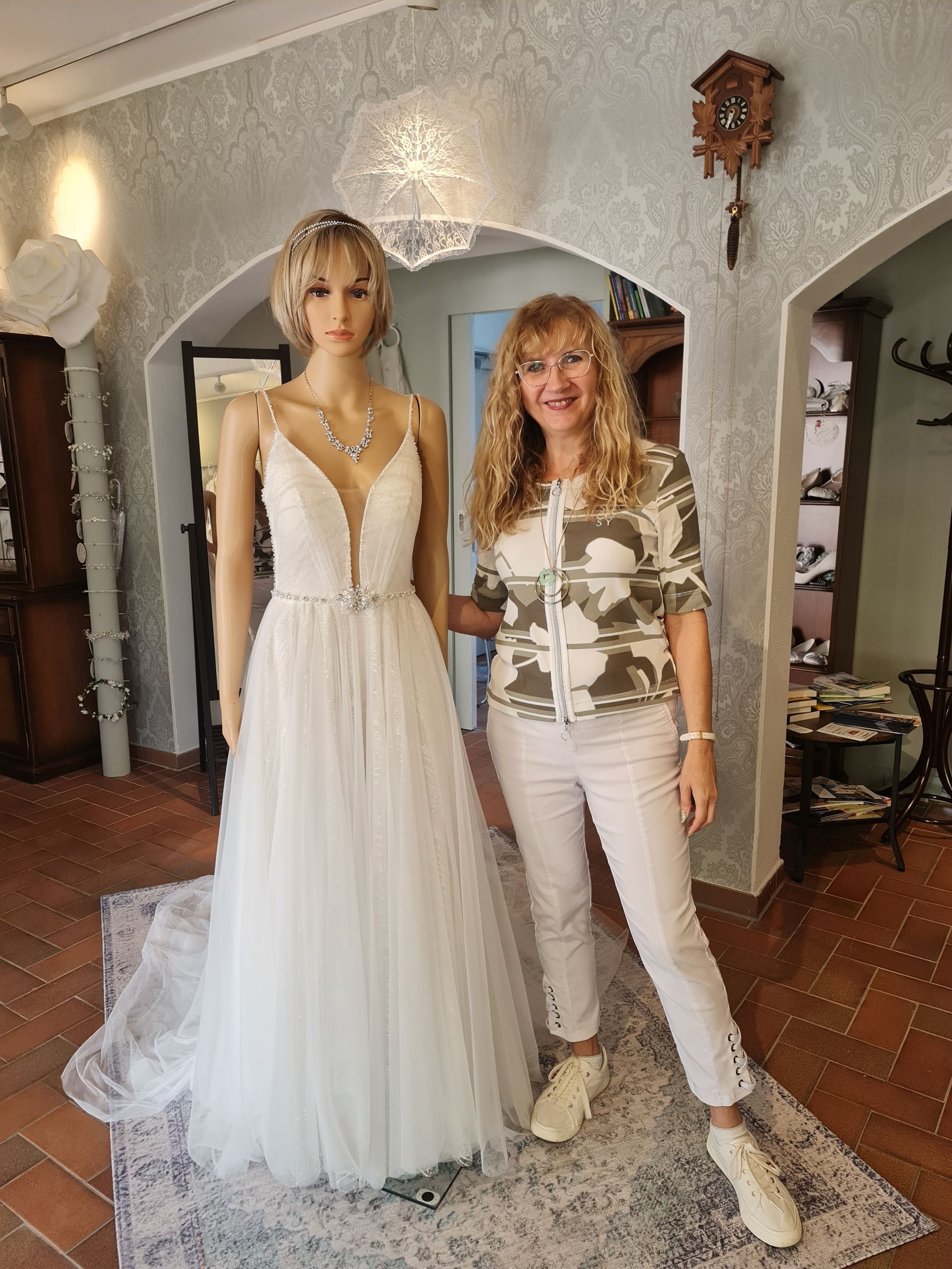 Frau mit einer Kleiderpuppe die ein Brautkleid trägt im Brautladen