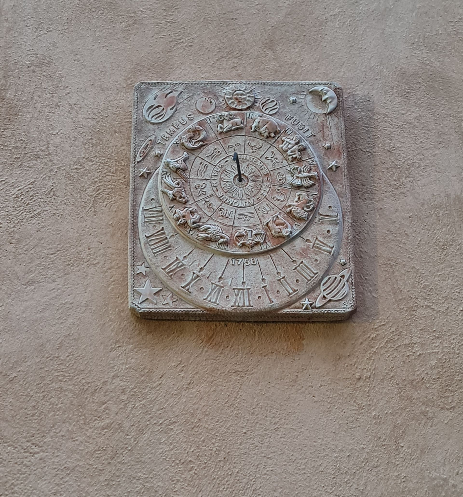 Sonnenuhr aus Stein an einer Hauswand