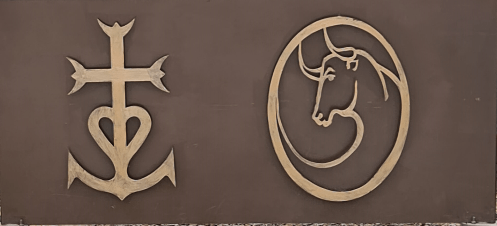 Kreuz der Camargue und ein zechen mit einem Stier in Goldfarbe auf braunem Untergrund