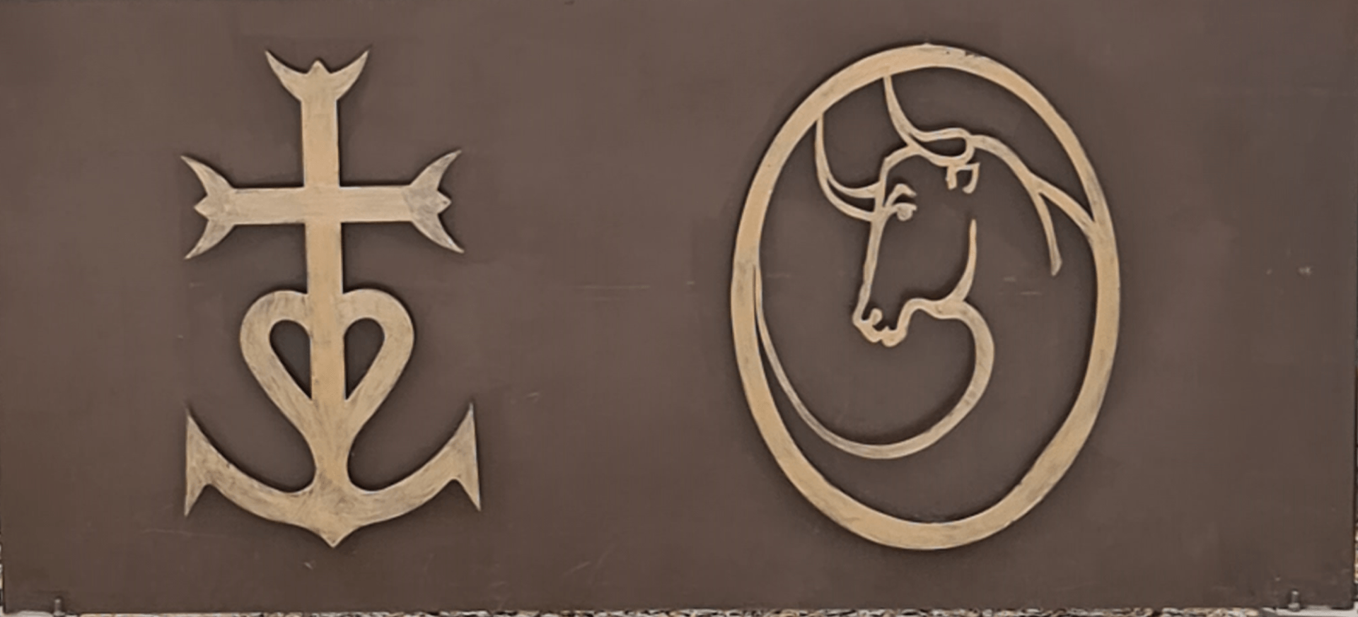 Kreuz und die Stiere Wahrzeichen der Camargue Photo by: Viola Einert-Krug Kreuz der Camargue und ein zechen mit einem Stier in Goldfarbe auf braunem Untergrund