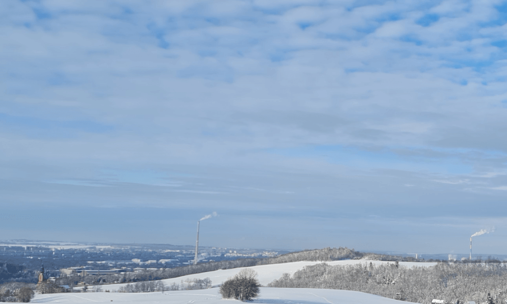 Stadt 'Chemnitz mit Schornsteinen im Tal Hügel und Wald ringsherum mit Schnee bedeckt