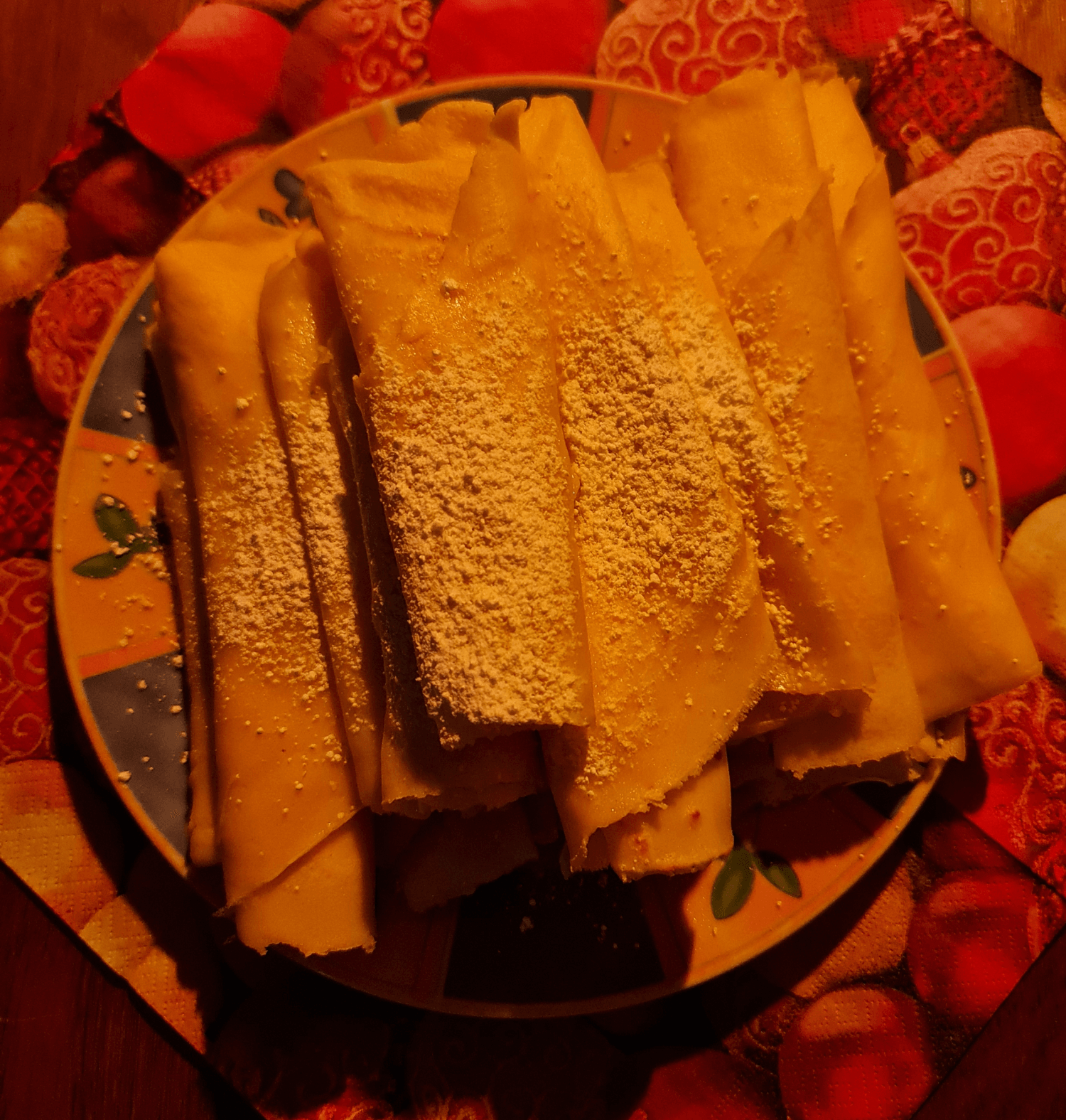 Crêpes mit Puderzucker Zusammengerollte hauchdünne Pfannkuchen liegen aufgestapelt auch einem Teller mit Puderzucker bestreut