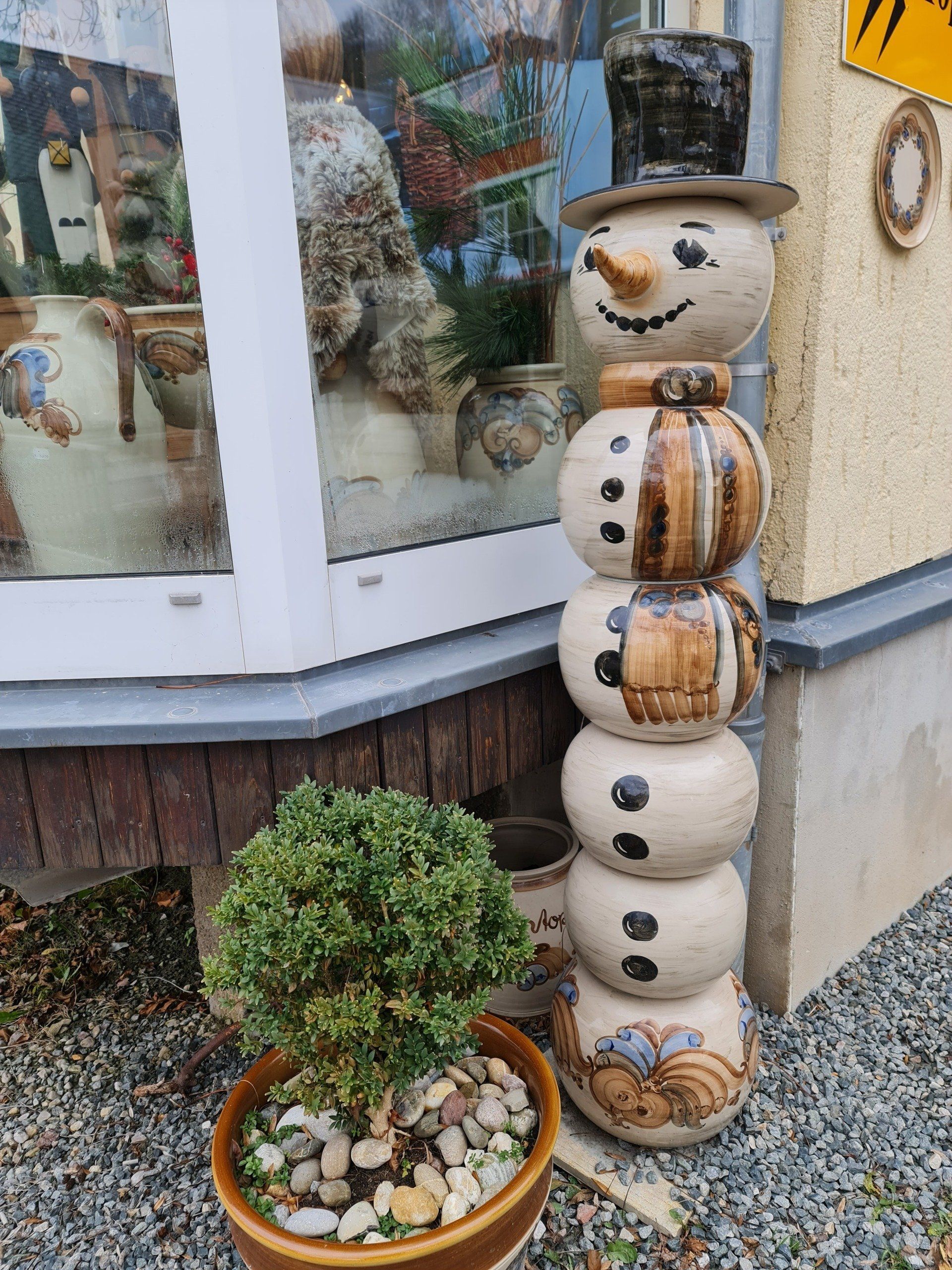 oranges Haus mit Balkon darauf eine großer weißer Engel und ein schwarzer Bergmann aus Holz gedrechselt und bemalt