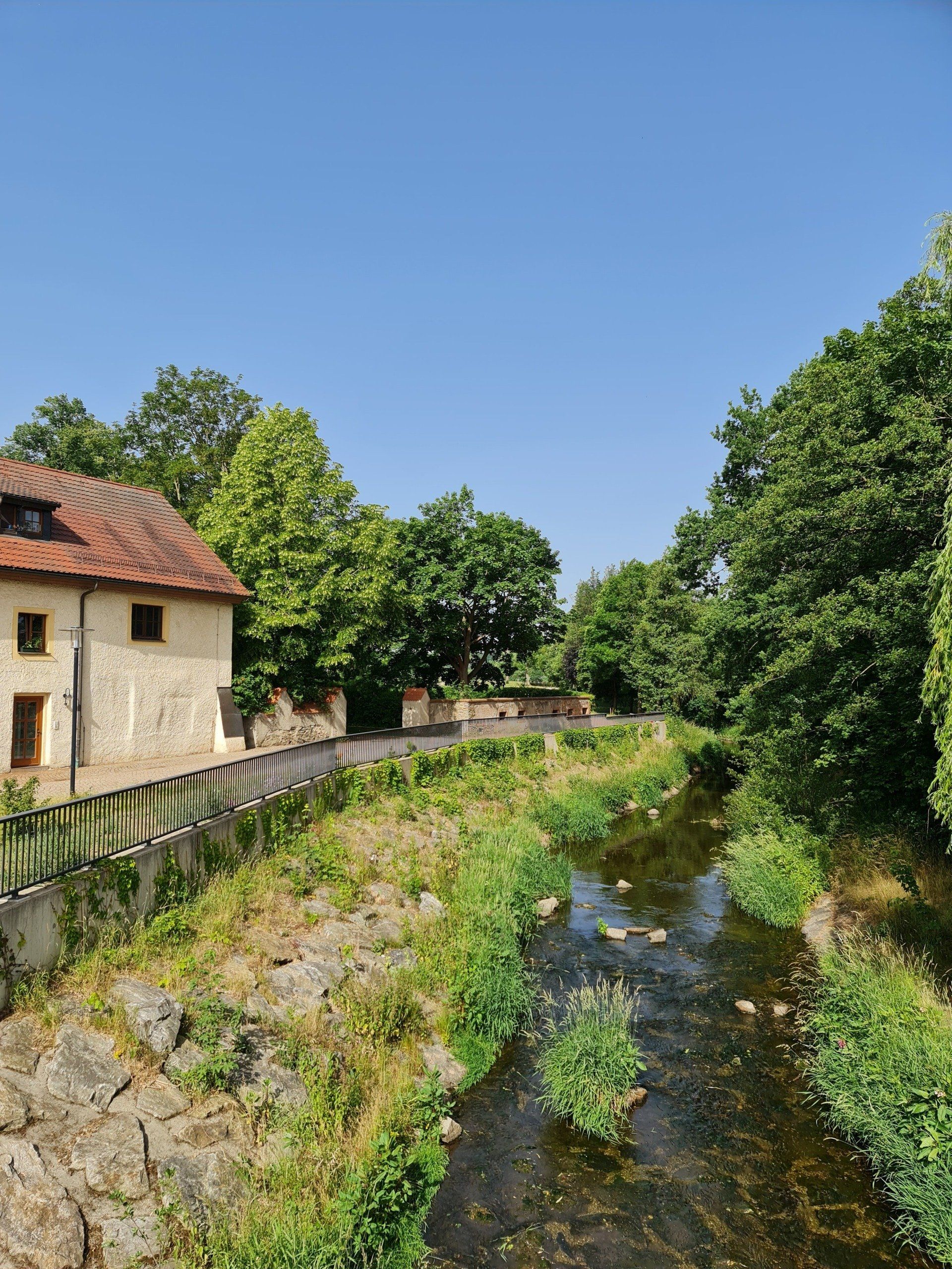 Flussbett mit Wasser im Grünen und ein Gebäude