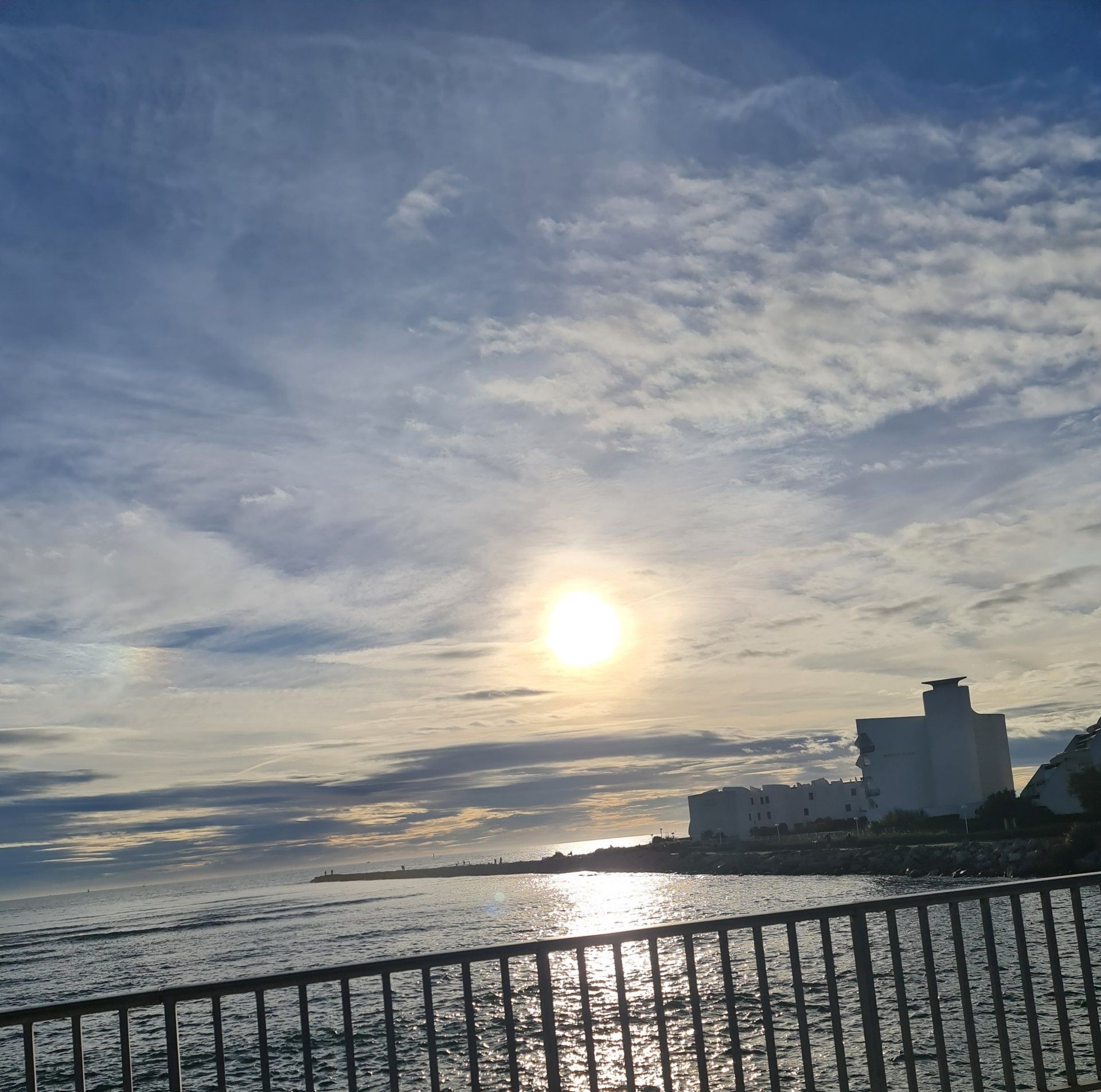 Blick von einer Brücke aus, es ist nur das Metallgeländer zu sehen , aufs Meer. rechterhand vorn im Meer weisse Häuser einer Ferienanlage
