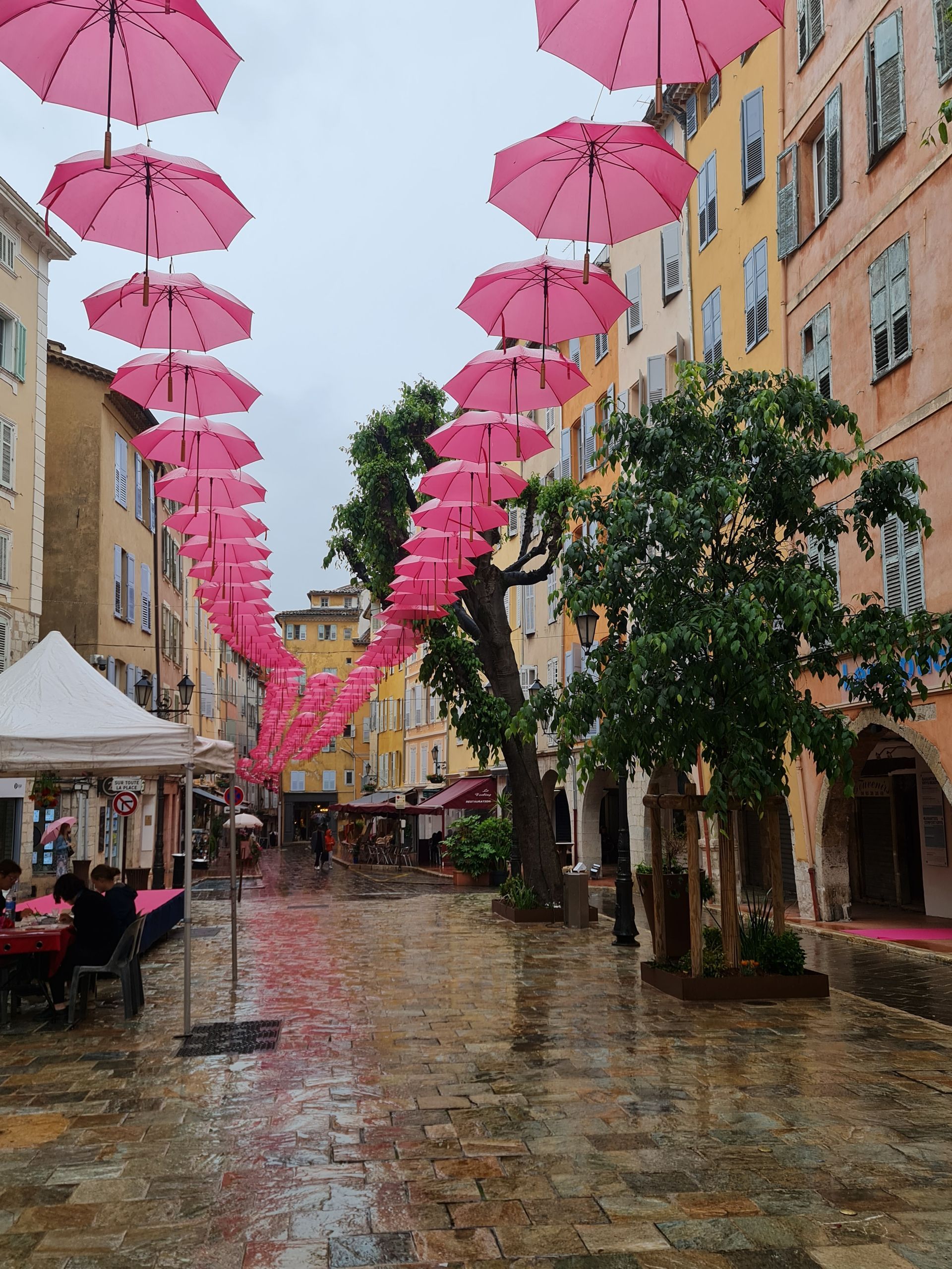 rosa Schirme in 2 Reihen über einer Straße