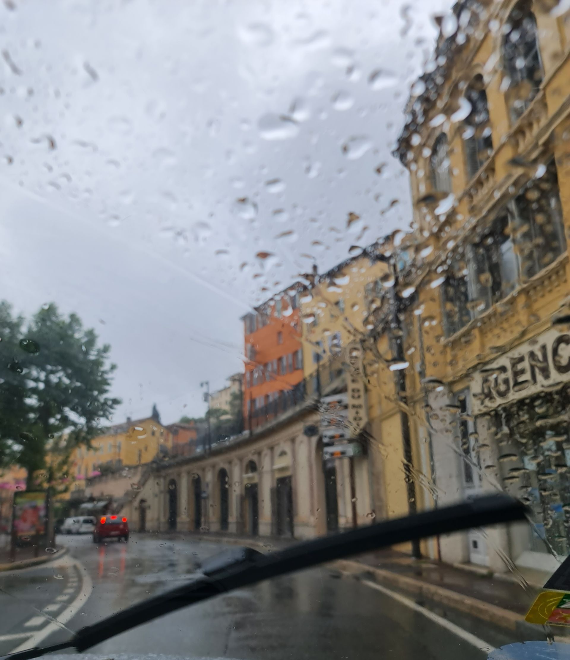südfranzösische Straße mit Steinhäusern im regen aus dem Auto fotografiert
