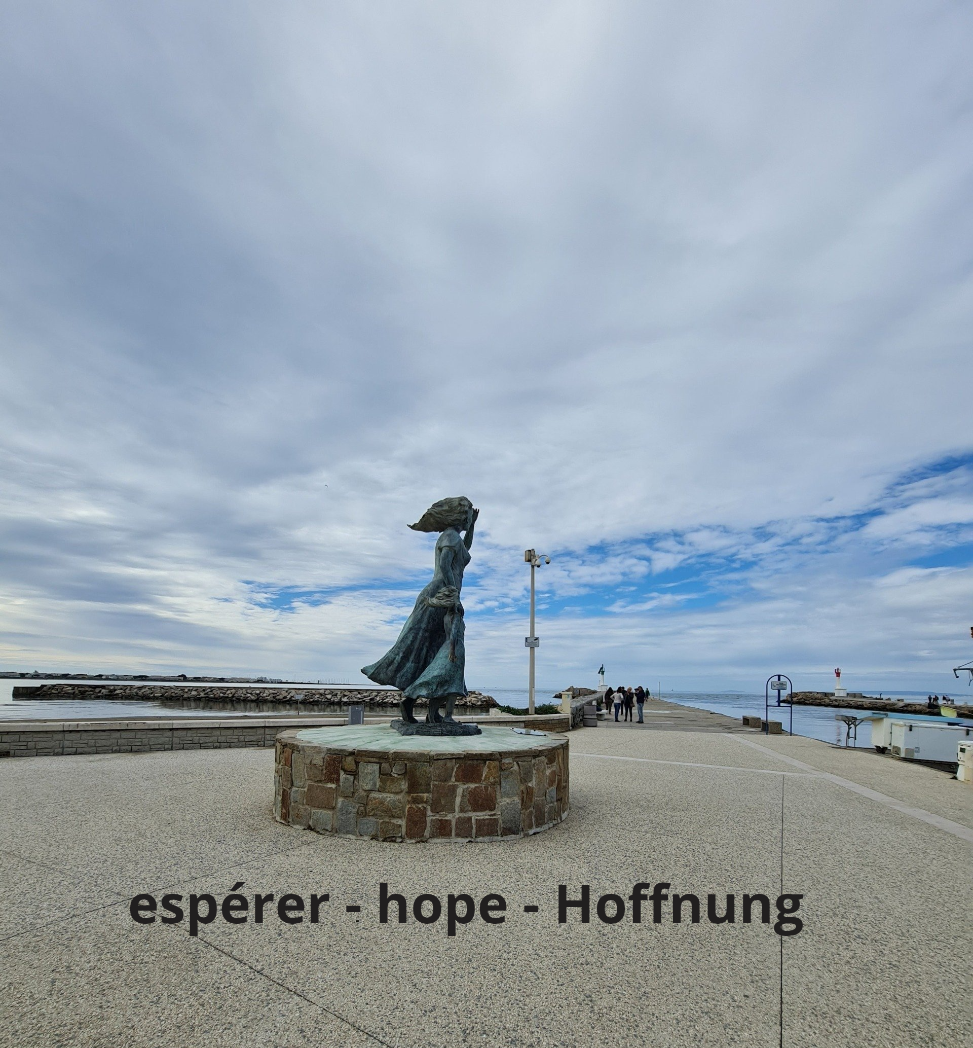 Denkmal  auf einem Sockel stehende Frau, die ihre Tochter an der Hand hält und aufs Meer schauen an der Mole in Le Grau du Roi spektakulärer Himmel mit fliehenden Wolken