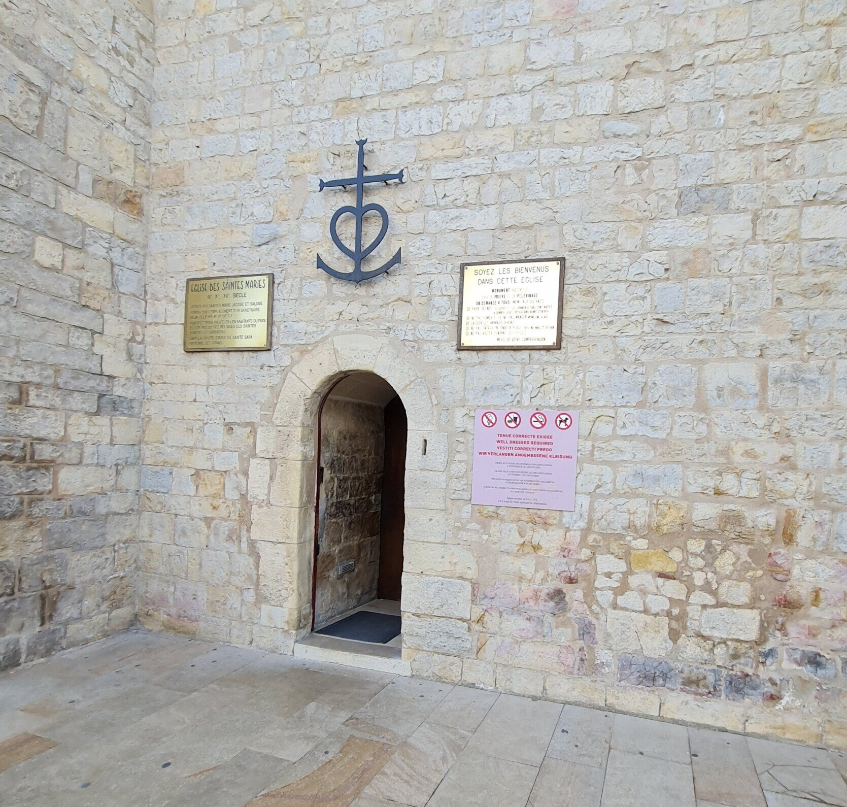 Kirche Notre-Dame-de-la-mer in Saintes-maries-de-la-Mer   Camargue    Photo by: Viola Einert-Krug Eingang zu einer Steinkirche mit einem Kreuz der Camargue darüber