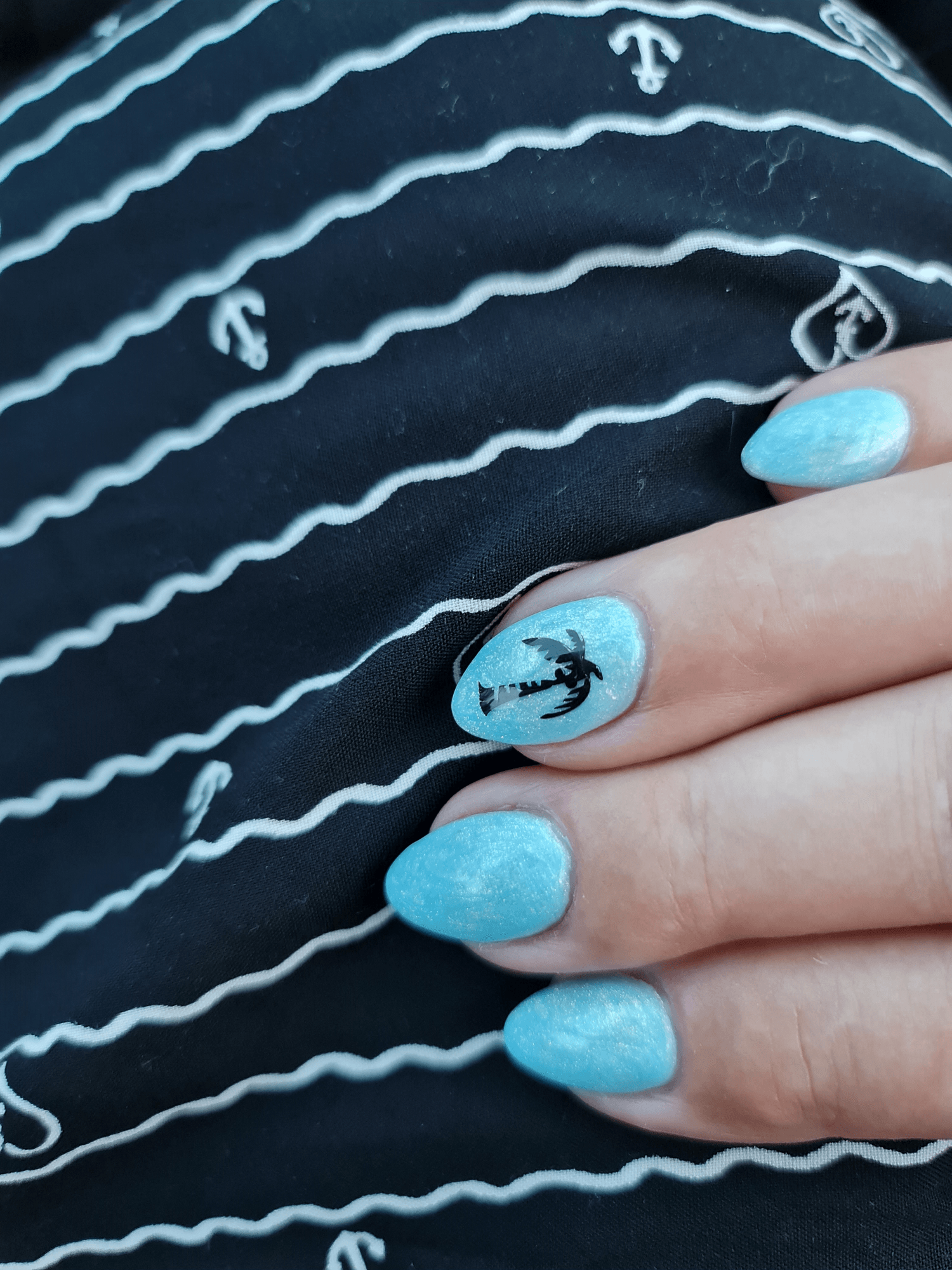 Textilie mit Wellen und Anker - Hand mit blauen Fingernägeln-Palme auf dem Fingernagel