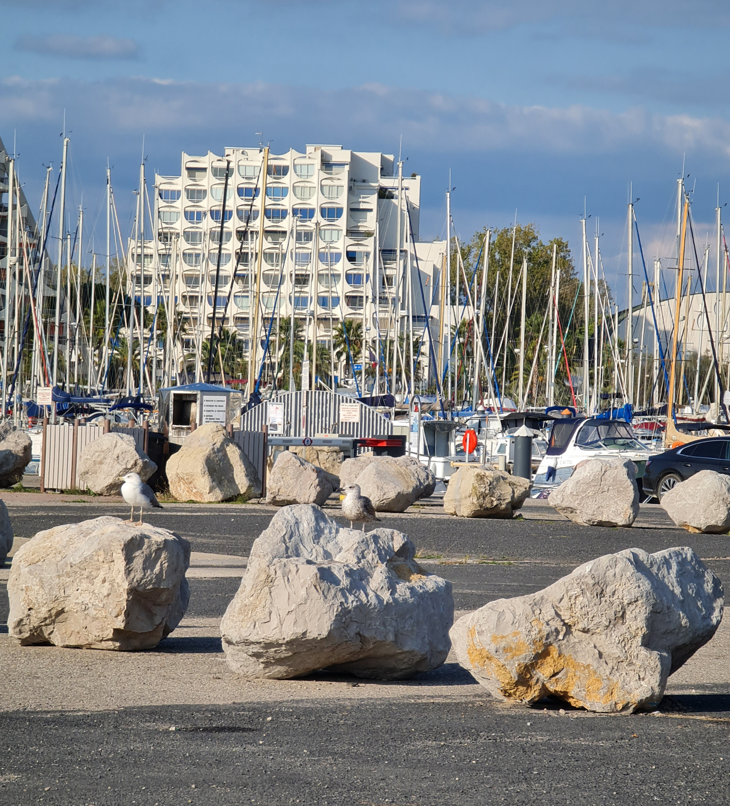 im Hintergrund weißen Gebäuden, die unterschiedliche futuristische Formen haben , davor Strand und dazwischen das Mittelmeer