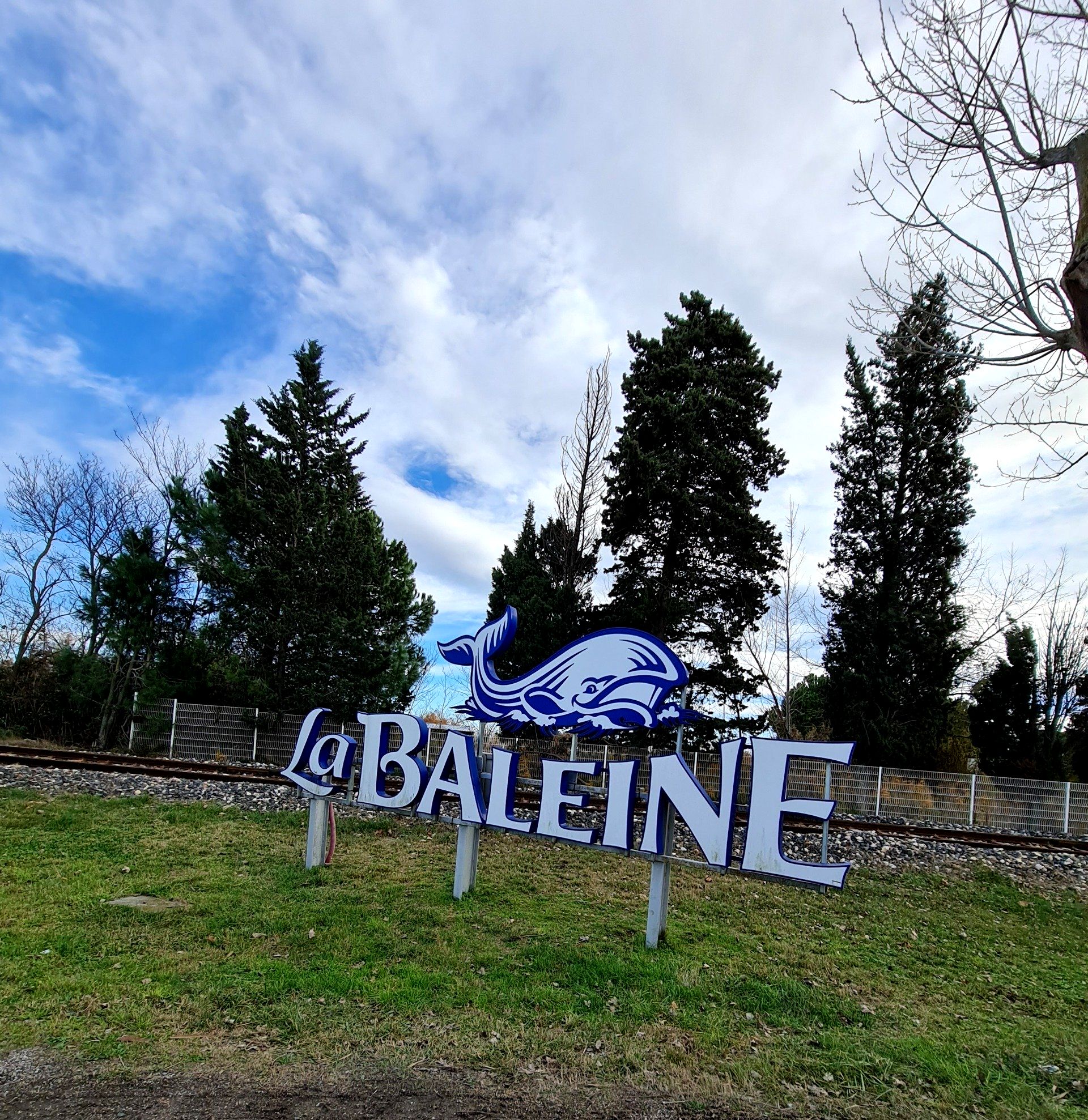 Ein Wal und die blaue Schrift La Baleine- Schild vor den Salins du midi