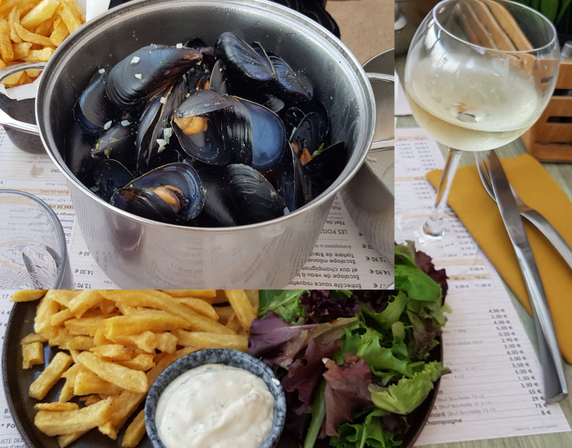 Schwarze Miesmuscheln im Topf auf dem Tisch dazu Pommes Frites und Salat mit Dip