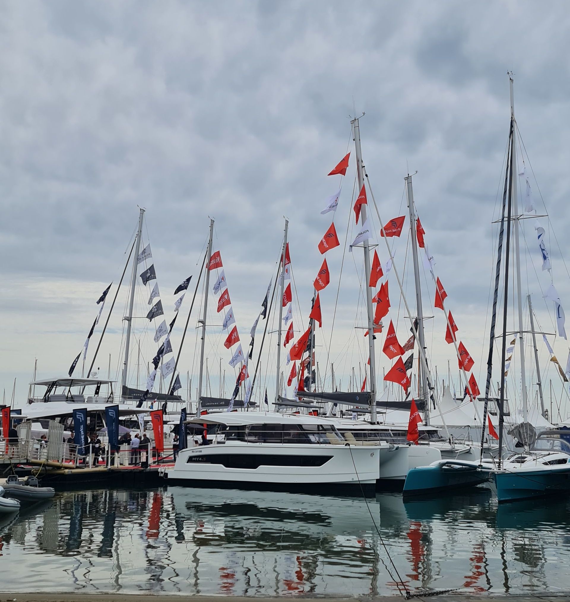 Katamarane im Wasser mit roten Fähnchen an den Segelmasten