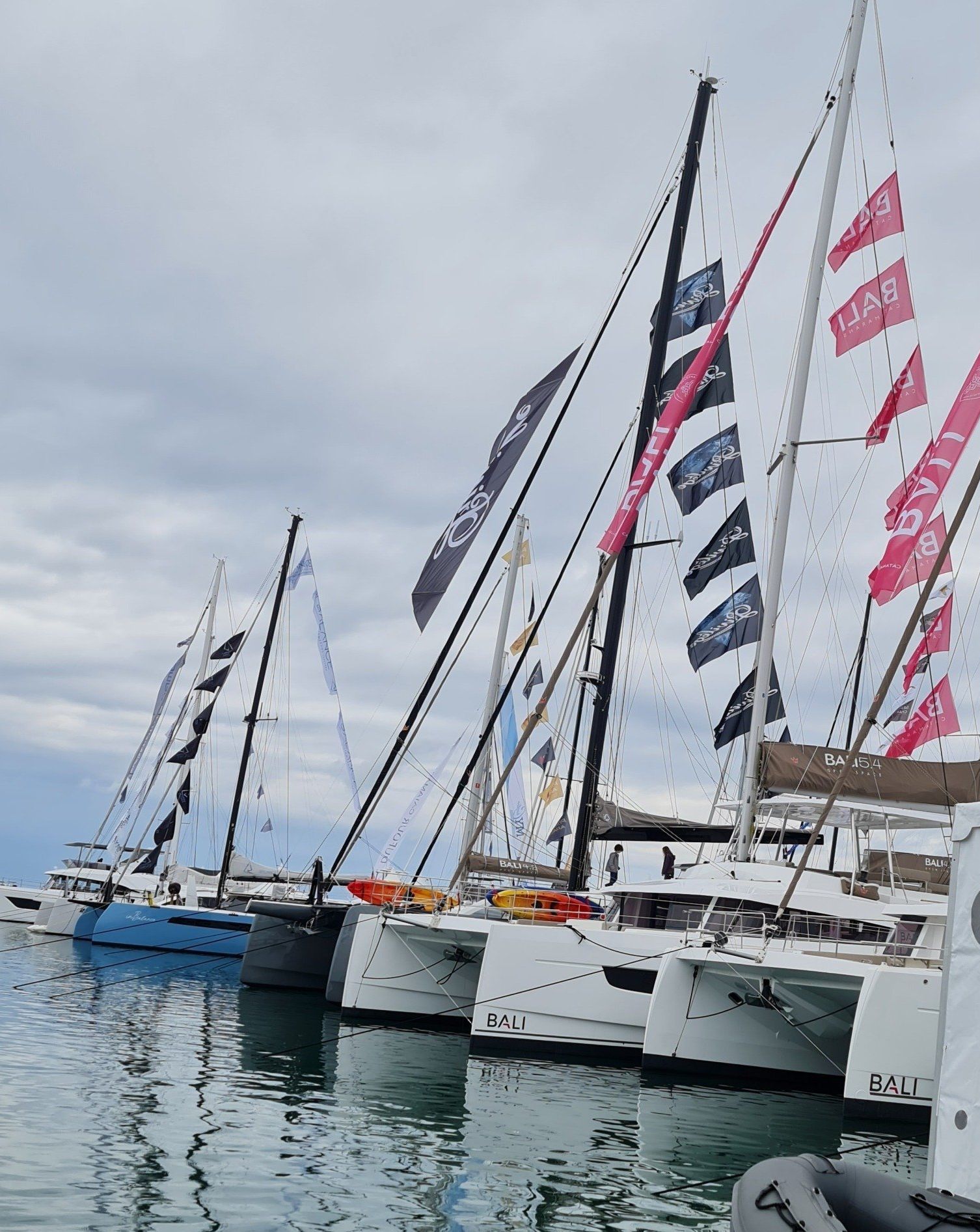 Katamarane auf einer Ausstellung im Meer mit Fähnchen in rot und blau an den Segelmasten