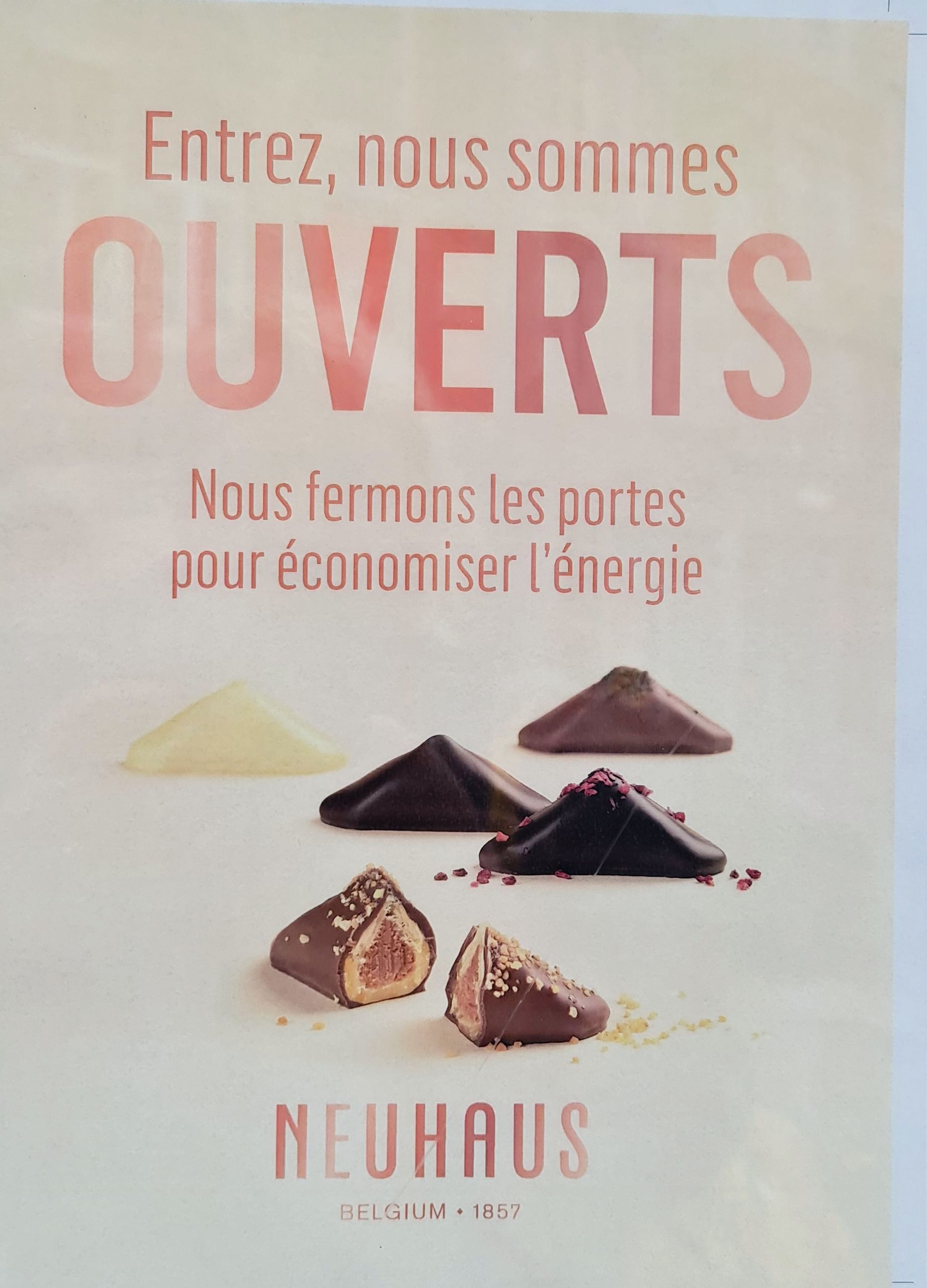 Schild von einem Geschäft, dass belgische Schokolade verkauft zu den Öffnungszeiten