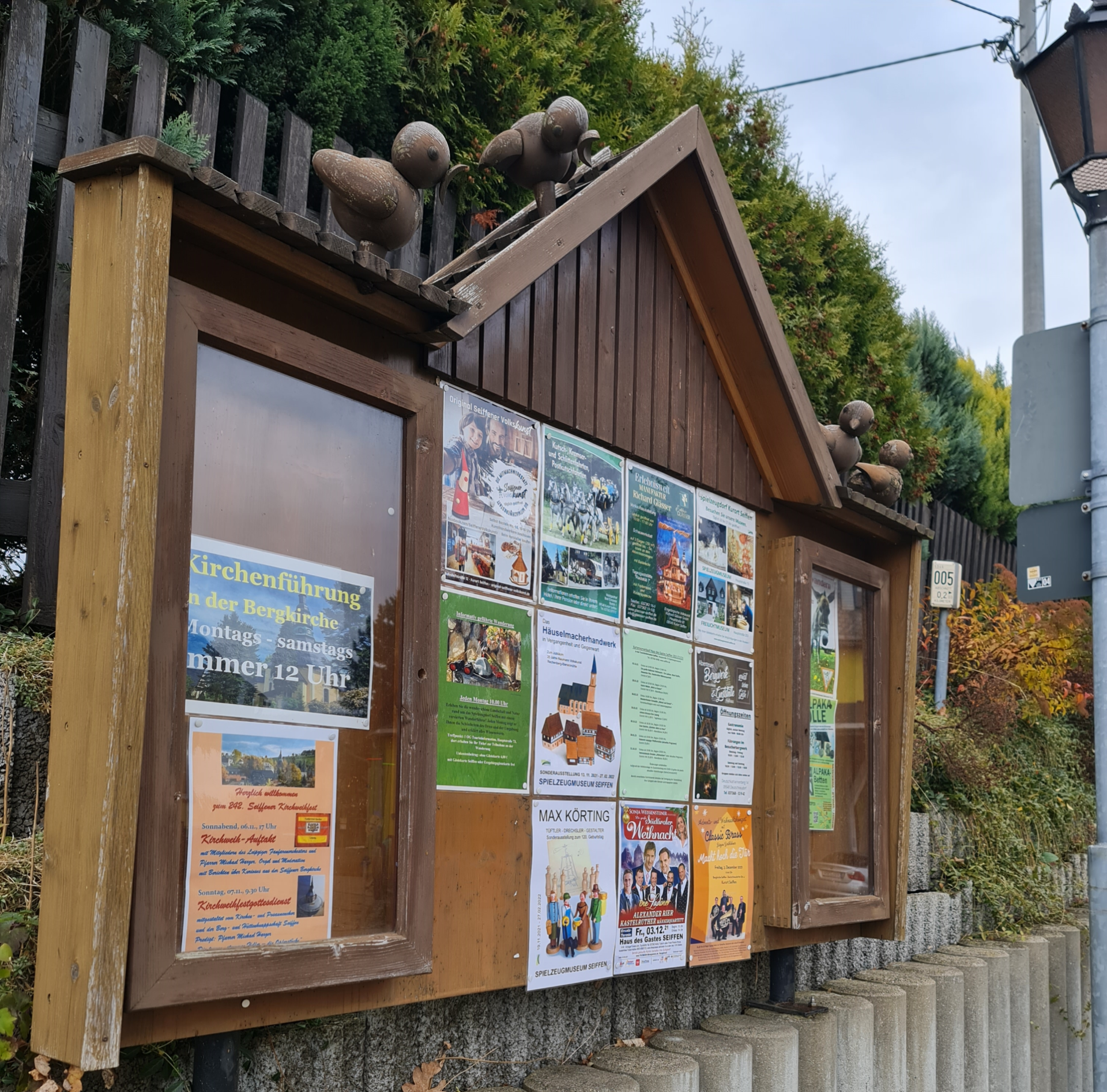Informationstafel aus Holz mit geschnitzten Holzvögeln darauf