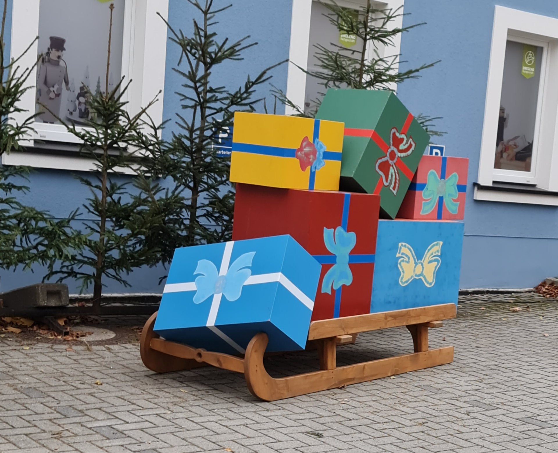 In Seiffen Erzgebirge weihnachtet es schon vor einem blauen Haus steht ein großer Schlitten mit bunten Paketen darauf